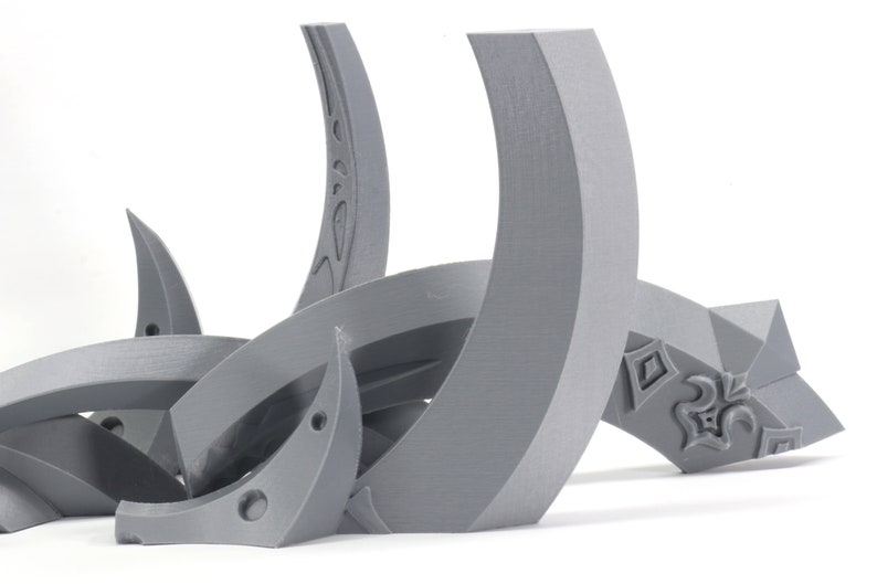 May include: A set of gray 3D printed plastic pieces that form a decorative design. The pieces are curved and have intricate details.