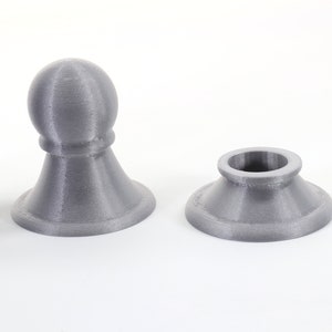 K&ouml;nnte beinhalten: Graue 3D-gedruckte Schachfiguren, darunter ein Bauer und eine Basis, vor wei&szlig;em Hintergrund. Die Figuren haben eine strukturierte Oberfl&auml;che und ein schlichtes Design. Der Bauer hat eine abgerundete Spitze.