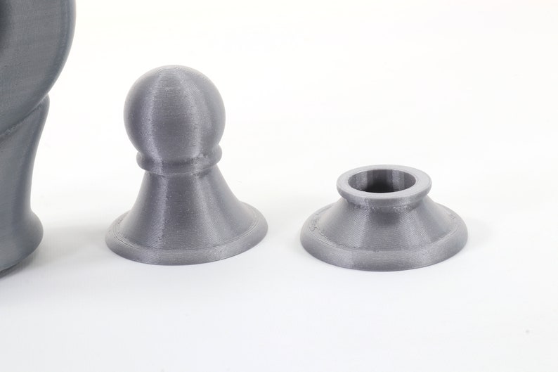 K&ouml;nnte beinhalten: Graue 3D-gedruckte Schachfiguren, darunter ein Bauer und eine Basis, vor wei&szlig;em Hintergrund. Die Figuren haben eine strukturierte Oberfl&auml;che und ein schlichtes Design. Der Bauer hat eine abgerundete Spitze.