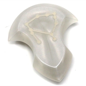 Op de afbeelding: Een wit, parelmoerachtig, onregelmatig gevormd, hars papieren gewicht met een wit Libra sterrenbeeld.