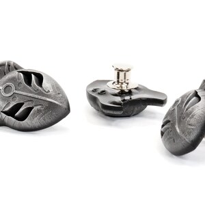 Op de afbeelding: Drie zilverkleurige metalen knopen met een gedetailleerd ontwerp van een gestileerd wolvenhoofd. De knopen hebben een pen- en lus sluiting.