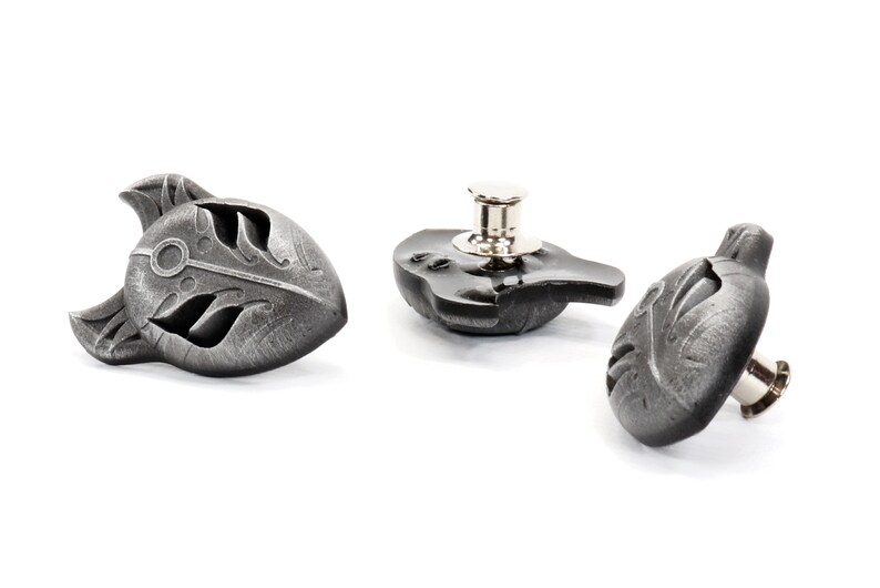 Op de afbeelding: Drie zilverkleurige metalen knopen met een gedetailleerd ontwerp van een gestileerd wolvenhoofd. De knopen hebben een pen- en lus sluiting.