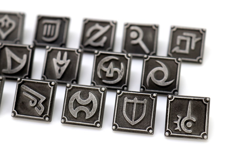 May include: A set of 11 silver-toned metal pins featuring various symbols, including a shield, a sword, and a crescent moon. The pins are arranged in a diagonal line on a white background.