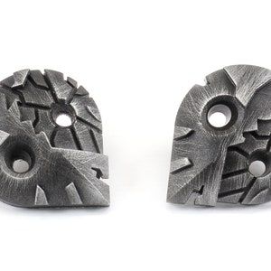 May include: Two silver metal buttons with a textured, geometric design. Each button has three holes.