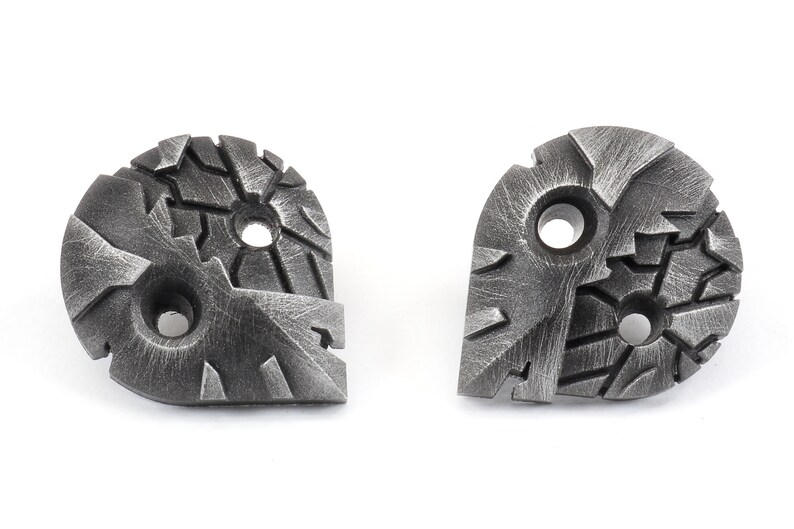 May include: Two silver metal buttons with a textured, geometric design. Each button has three holes.