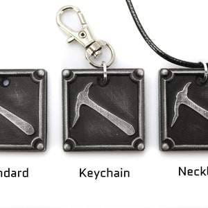 May include: Three square, metal pendants with a pickaxe design. One is a standard pendant, one is a keychain, and one is a necklace. The pendants are dark gray with a silver pickaxe and are labeled "Standard", "Keychain", and "Necklace".