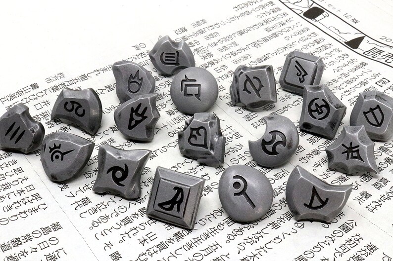 May include: A collection of 15 silver-colored metal dice with various symbols and designs. The dice are scattered on a white surface with Japanese text.