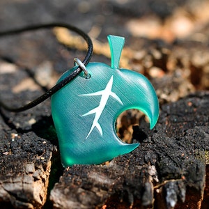 May include: A teal green leaf-shaped pendant necklace with a white leaf design. The necklace is made of resin and has a black cord.