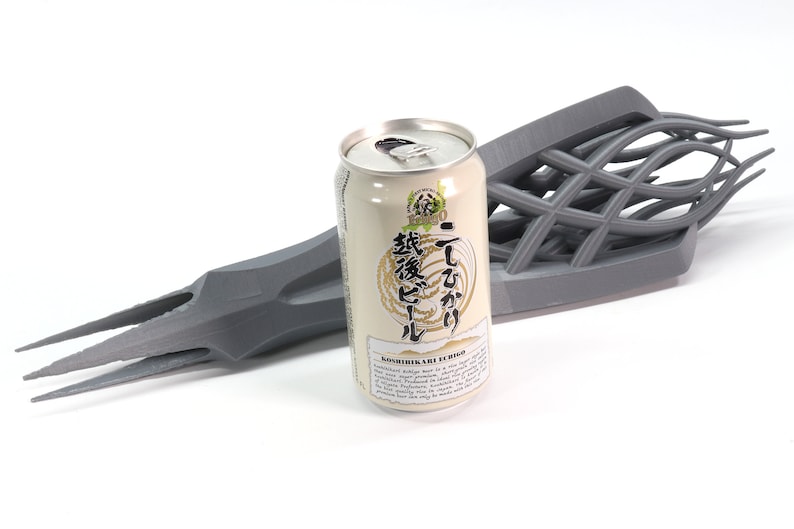 May include: A gray 3D printed object shaped like a hand holding a can of Japanese beer. The can is labeled "Echigo" and has Japanese text on it.