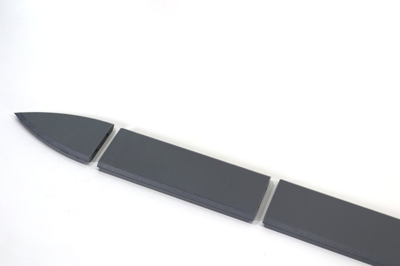 Puede incluir: Una espada gris se desmonta en cuatro piezas. La espada est&aacute; hecha de un material duro y duradero y tiene una punta afilada.