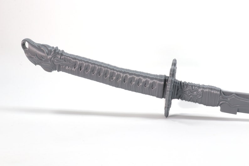 May include: A gray 3D printed sword with a dragon head handle and a detailed blade.