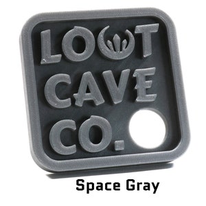 May include: A gray plastic key chain with the text "LOOT CAVE CO." and a small hole in the center. The key chain is a square shape with rounded corners.