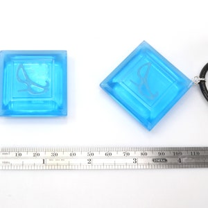 May include: Two blue glass pendants with a white etched design. One pendant is on a black cord.