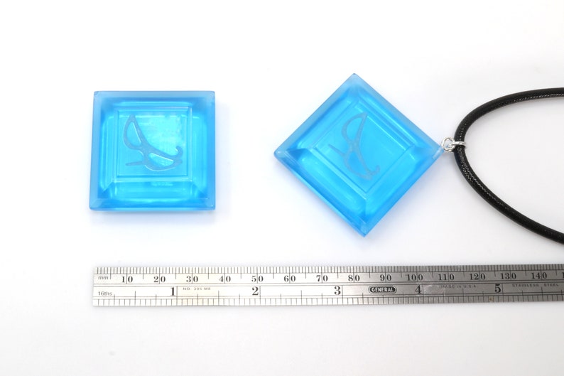 May include: Two blue glass pendants with a white etched design. One pendant is on a black cord.