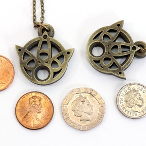 May include: Two gold-toned necklaces with intricate Celtic knot designs. The pendants are about the size of a US penny.