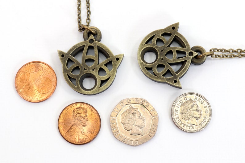 May include: Two gold-toned necklaces with intricate Celtic knot designs. The pendants are about the size of a US penny.