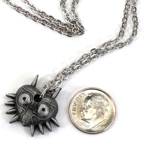 May include: A silver necklace with a Majora's Mask pendant. The pendant is about the size of a US dime.