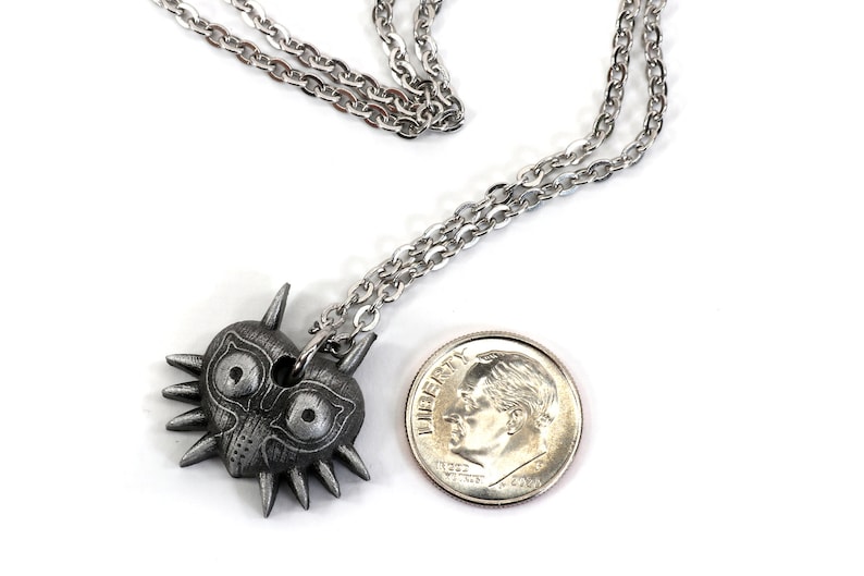 May include: A silver necklace with a Majora's Mask pendant. The pendant is about the size of a US dime.