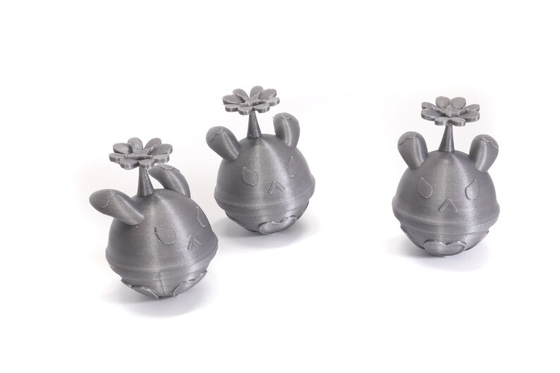 May include: Three gray 3D printed figurines of a cartoon character with a flower on top. The character has a round body, two ears, and a small nose.