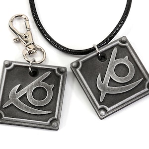 May include: Two silver-toned pendants with a stylized eye symbol on a black cord necklace and a silver-toned keychain.