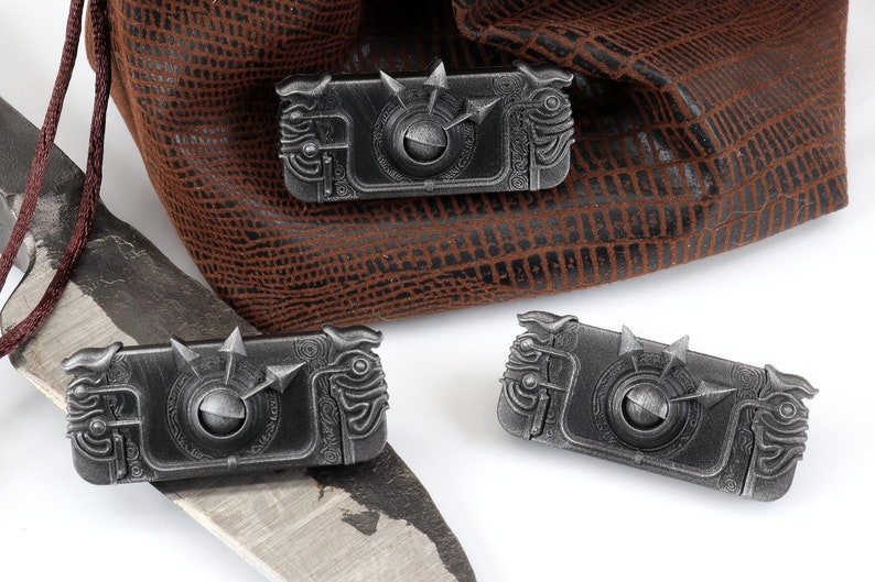 May include: Three silver metal dice with intricate designs and a spinning wheel in the centre. The dice are on a white surface.