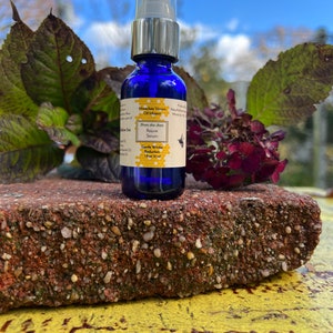 May include: A blue glass bottle with a silver pump top. The bottle is labeled "Honeybee Venom Oil Infusion" and "From the Bees Rejuve Serum". The label also says "Gentle Wrinkle Reduction" and "1 fl oz / 30 ml".