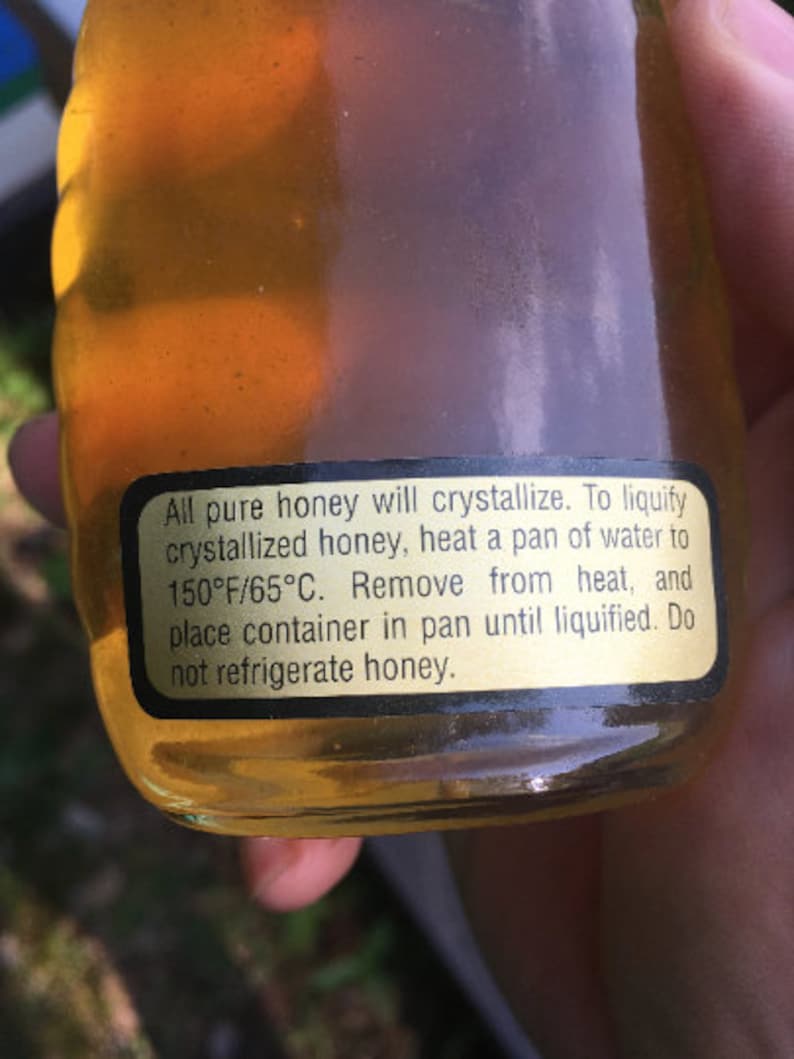 May include: A glass jar of honey with a black label that reads: "All pure honey will crystallize. To liquify crystallized honey, heat a pan of water to 150&deg;F/65&deg;C. Remove from heat, and place container in pan until liquified. Do not refrigerate honey."