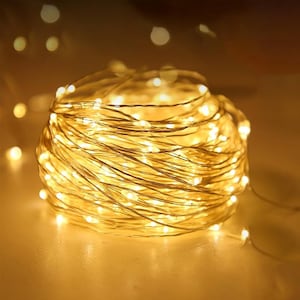 May include: A coiled string of warm white LED fairy lights. The lights are small and evenly spaced along a thin, flexible wire. The overall effect is a soft, glowing ball of light, perfect for decorative purposes.