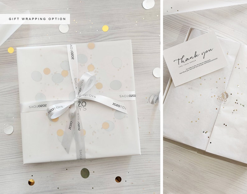 May include: White gift box with a white ribbon and gold confetti. The ribbon has the text "ZOZOTOYS" printed on it. The box is sitting on a white wooden surface. A thank you card is included with the gift.