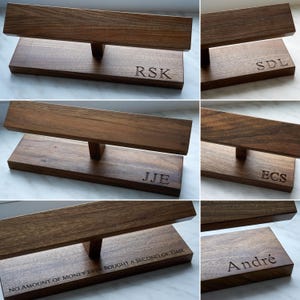 May include: Six wooden watch stands with different engraved names. The names are RSK, SDL, JJE, ECS, NO AMOUNT OF MONEY EVER BOUGHT A SECOND OF TIME, and Andr&eacute;.