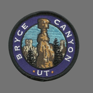 May include: A round, purple and black embroidered patch with the text "Bryce Canyon - UT" and a depiction of a tall, orange rock formation in a landscape.