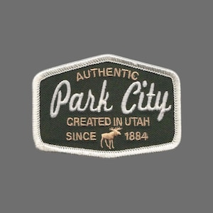 Peut inclure: Un écusson brodé blanc et vert avec le texte "Authentic Park City Created in Utah Since 1884" et une silhouette d'élan.