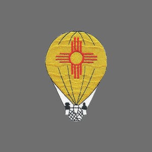 May include: Embroidered patch depicting a yellow hot air balloon with the New Mexico Zia sun symbol in red. The balloon has black stitching and a white base. Suitable for clothing or accessories.