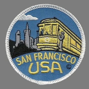 May include: A blue and white embroidered patch with a yellow trolley car, a cityscape, and the text "SAN FRANCISCO USA".