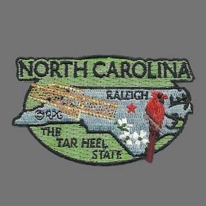 Peut inclure: Un écusson brodé représentant un contour vert de l'état de Caroline du Nord avec les mots "North Carolina, The Tar Heel State" et un cardinal rouge. La capitale de l'état, Raleigh, est marquée d'une étoile rouge.