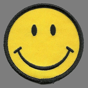 May include: A yellow smiley face patch with a black stitched border. The smiley face has black eyes and a curved black mouth, creating a classic happy expression. The patch is round and made of fabric.