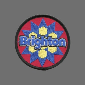 May include: A red, blue, and yellow embroidered patch with the word "Brighton" in blue lettering.