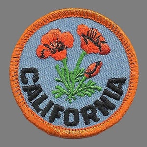 May include: A round, orange-bordered patch with a blue background. The patch features two orange poppy flowers with green stems and leaves. The word "CALIFORNIA" is embroidered in black around the edge of the patch.