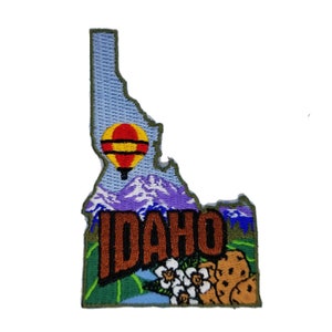 May include: Embroidered patch shaped like the state of Idaho with the word "IDAHO" in brown letters, a hot air balloon, mountains, and a flower with a potato.
