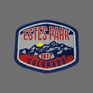 May include: A blue, red, and white embroidered patch with the text "ESTES PARK 1917 COLORADO" and a depiction of mountains and a sun.