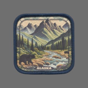 May include: A blue embroidered patch with a scenic image of a mountain range, a river, and two bears. The text "ALASKA" is printed at the bottom of the patch.