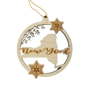 May include: A wooden Christmas ornament shaped like a circle with a cutout of the state of New York. The ornament is decorated with snowflakes and the words "New York".