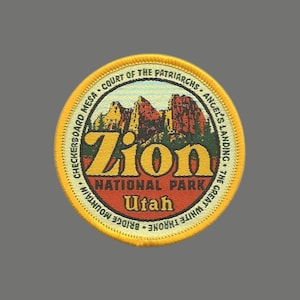 May include: A yellow and red round patch with the text "Zion National Park Utah" and a depiction of red rock formations. The text around the edge reads "Checkerboard Mesa, Court of the Patriarchs, Angel's Landing, The Great White Throne, Bridge Mountain."