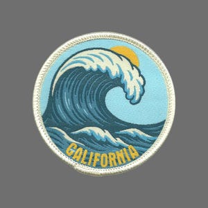 May include: Round patch featuring a stylized ocean wave in shades of blue and white, with a yellow sun in the background. The word "CALIFORNIA" is embroidered in yellow. The patch has a white stitched border.