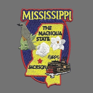May include: An embroidered patch featuring the state of Mississippi, with the text "The Magnolia State" and "Mississippi" in yellow. The patch also includes a bird, a magnolia flower, and a steamboat.
