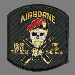 Peut inclure: Un écusson brodé noir et or avec un crâne portant un béret rouge et des fusils croisés. Le texte indique "AIRBORNE" au-dessus du crâne et "MESS WITH THE BEST DIE LIKE THE REST" en dessous.