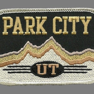 Peut inclure: Patch brodé avec les mots "PARK CITY UT" en lettres dorées sur fond noir. Le patch représente une chaîne de montagnes stylisée en fil doré et brun. Le patch a une bordure blanche avec un bord cousu.