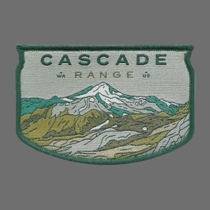 May include: A green embroidered patch with the text "CASCADE RANGE" and the abbreviations "WA" and "US". The patch features a stylized image of a mountain range with a snow-capped peak.