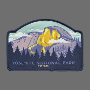 May include: A blue embroidered patch with a depiction of Half Dome, a famous rock formation in Yosemite National Park, California. The patch features a yellow and purple mountain range with a blue sky and white clouds. The text "Yosemite National Park Est. 1890" is embroidered in yellow on the patch.