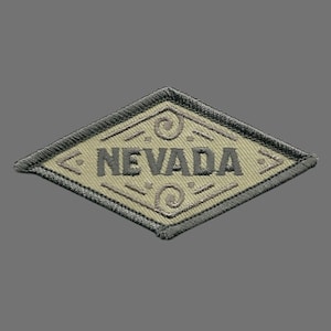 May include: A tan diamond-shaped patch with a gray border and the word "NEVADA" embroidered in gray letters.